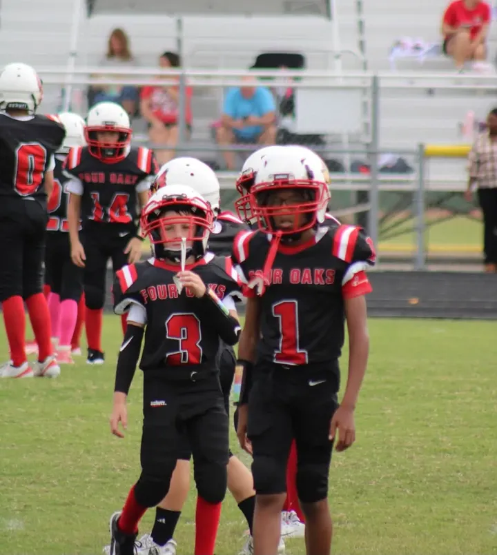 Four Oaks JV players in black Four Oaks jerseys walking onto the field at South Johnston