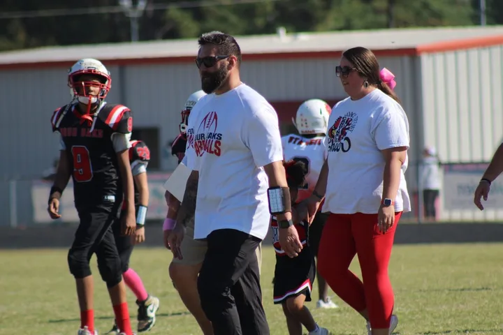 A Four Oaks coach walking the sideline with Four Oaks players