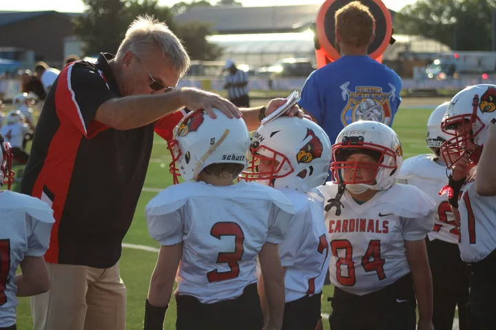 A Four Oaks coach talking with young players on the sideline