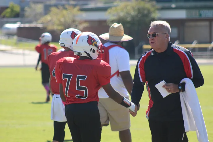 A Four Oaks coach checking in with a player during a game