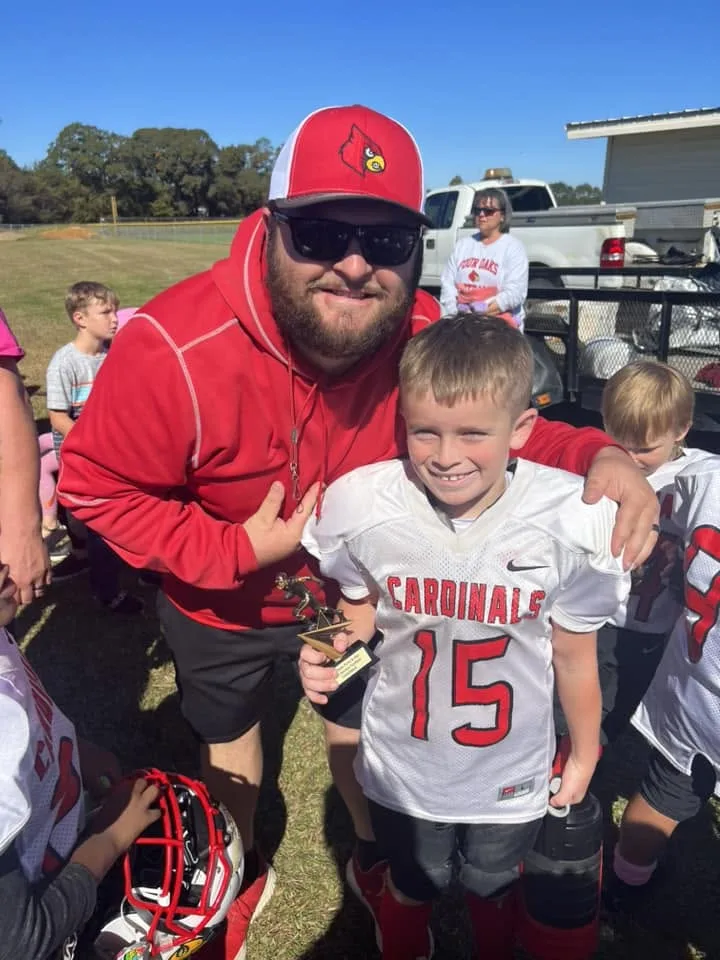 A Four Oaks coach with a young player on the sideline