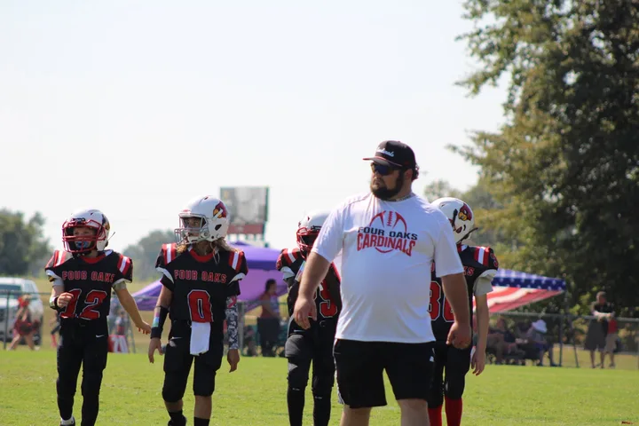 A Four Oaks coach walking onto the field with players