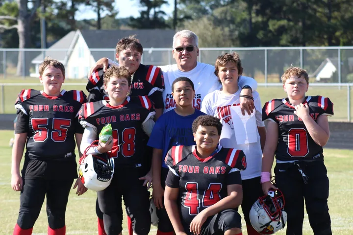 Four Oaks coaches with their players after a game