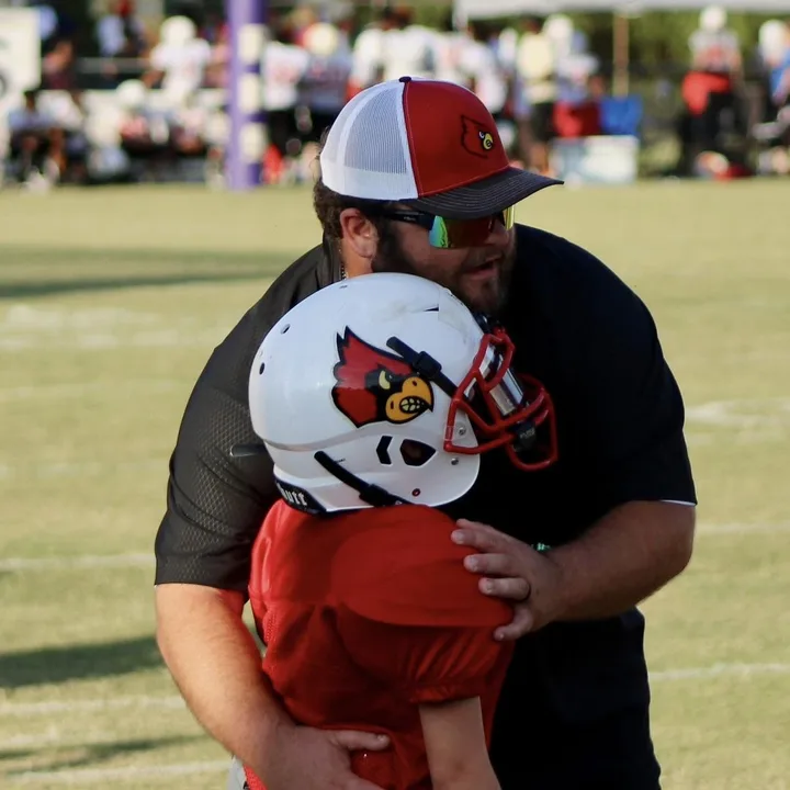 A Four Oaks coach hugging a young player after a game