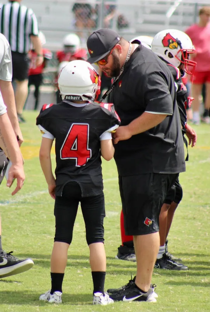 A Four Oaks coach helping a young player with his jersey before a game