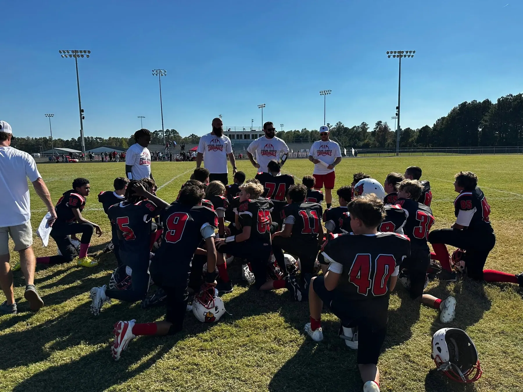 Four Oaks players and families gathered on the field after a game