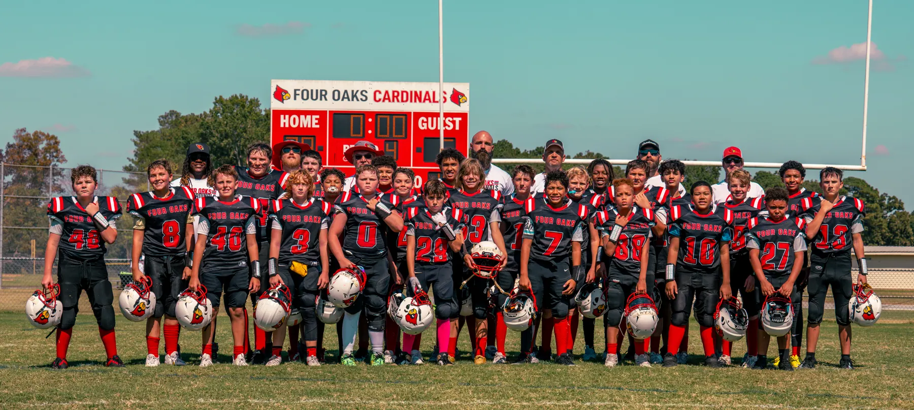 Four Oaks Cardinals team photo in front of the scoreboard